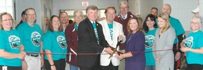 Dr. David Thompson, superintendent of Stewartville Public Schools, front and center in the dark suit; Rob Mathias, School Board chairman, in white coat; and Sheila McNeill, principal of Bear Cave Intermediate School, cut the ribbon to officially open the new school on Saturday morning, Oct. 1. From left are Maryan Gisler, administrative assistant at Bear Cave School; current or former School Board members Dean Mikel, Tara Stockman, Mark Vaupel, Joe Waugh, Rod Morlock, Angela Payton,Todd Emanuel and Lori Miller-Beach, along with Joyce Jorde, administrative assistant at Bear Cave School.