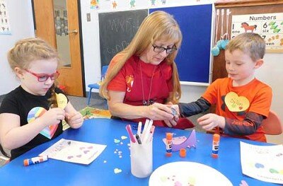 Kathy Dux, who teaches a butterfly class at the St. Johnís Wee Care Learning Center, works on a pre-Valentineís Day project with Wee Care students, from left, Vivian Christie, 4 1/2, of Stewartville, and Dylan Meyer, 5 1/2, of Racine, during a Wee Care class on Tuesday morning, Feb. 11.