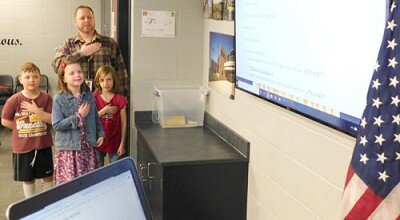 With assistance from Zane McInroy, principal of Bonner Elementary School, Bonner students, from left, second graders Garrett Colligan and Madelyn Bergey, along with first grader Reese Schatz, lead the Pledge of Allegiance to kick off the Stewartville School Board’s regular meeting on Monday evening, March 9.
