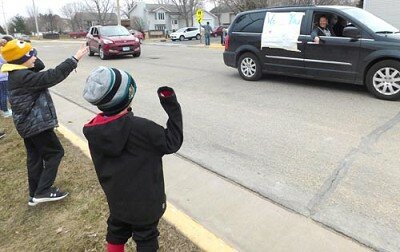 Young students lined up along the side of the street near Bonner Elementary School wave to Tyne Wynn, an art teacher at Bear Cave Intermediate School, above, as Carly Larson, a first grader at Bonner, at left below, and her mother Tanya, enjoy the teachers parade on Tuesday, March 24.