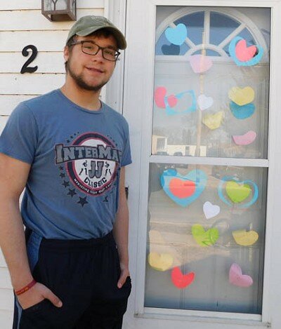 Christian Sackett stands near his front door, covered with hearts of many colors.