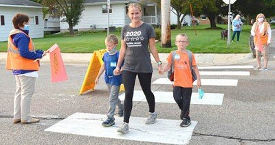 Assisted by crossing guards Joyce Meldahl, left, and Linda Holtan, right, Linda Meyer walks across the street hand-in-hand with her two sons, Lucas, left, and Dylan, before the first day of classes at Bonner Elementary School on Monday morning, Sept. 14.