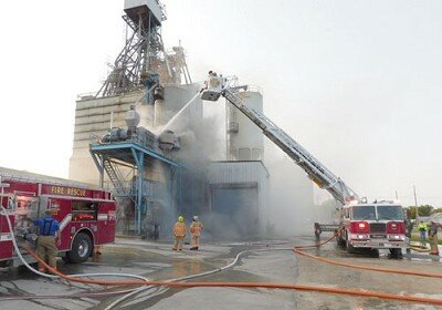 Stewartville firefighters used the departmentís new ladder truck to attack a fire at All American Co-op on Thursday morning, Sept. 17. A soybean roaster at the Co-op caught fire, sending a column of smoke into the air.