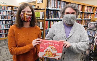 Sarah Schramek, an aide at the Stewartville Public Library, left, and Nate Deprey, library director, display one of the 120 Build Your Own Gingerbread House kits Deprey purchased from Five Below in Rochester. Beginning Monday, Dec. 7, local and area residents may take home a free, already-constructed house.
