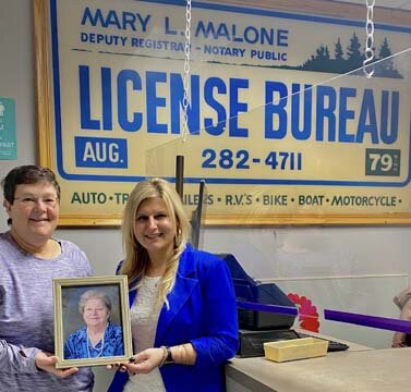 Molly Hintz, left, and Lacie Tingesdal, license bureau owners, share a photo of Mary Malone, Mollys mom and Lacies grandmother