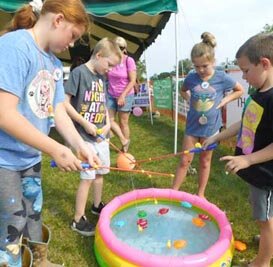 FUN WITH FISHING -- From left, Lora Ingalls, a third grader at BCI; Lincoln Cappell of Rochester; Kendall Ryan, a third grader at BCI; and kindergartner Bronson Dube, enjoy a fishing game at Old Settlers Day.