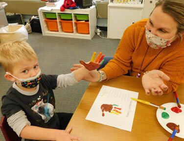 Joey Breen, 3, assisted by Nashia Baldus, early childhood teacher, displays a turkey imprint on his hand and the printed page at the Central Education Center on Thursday, Nov. 18.
